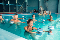 Wassergymnastik, Eine Gruppe von Menschen übt mit Hanteln im Schwimmbecken